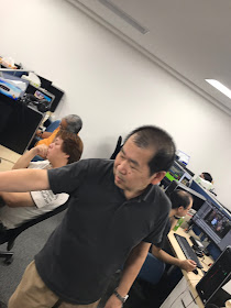 Yu Suzuki at the development studio, with the team hard at work
