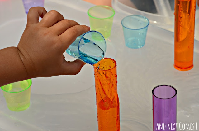 Toddler pouring water into colorful cups