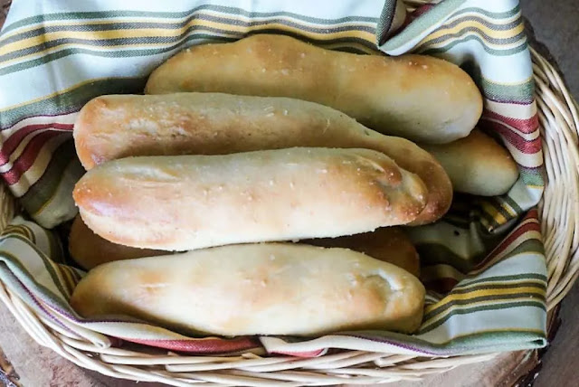 Italian Breadsticks are the perfect finishing touch to any meal. These Olive Garden Copycat Breadsticks are soft and buttery and take less time than you'd think. Don't let the yeast scare you off because these breadsticks are worth the effort!  Yield: 12 BREADSTICKS Prep Time: 20 MINUTES Cook Time: 12 MINUTES Rising Time: 30 MINUTES Total Time: 1 HOUR 2 MINUTES  ✅ INGREDIENTS  FOR THE BREADSTICKS 1 1/2 cups warm water 2 Tbsp sugar 2 pkgs Active Dry Yeast 1 Tbsp salt 2 Tbsp butter, softened 4-5 cups flour  FOR GARLIC BUTTER: 6 Tbsp butter, melted 1/2 tsp garlic powder sea salt  ✅ INSTRUCTIONS Preheat oven to 170 degrees F.  Pour warm water in bowl of stand mixer with sugar and yeast. Let sit for 10 minutes until yeast froths.  Add salt, butter, and 2 cups flour. Mix on low until combined. Add the rest of the flour 1/2 cup at a time until the dough pulls away from the side of the bowl. (I used just under 4 cups of flour.) Knead dough in stand mixer on low-medium speed about 5 minutes until dough is soft and easy to work with. Roll dough into long log then cut into 12-14 equal pieces. Take each piece and roll into a 6-inch long snake. Place breadstick dough on two grease cookie sheets, leaving about 2 inches between each. Place both cookie sheets in 170 degree oven for 20-30 minutes until doubled in size. Remove pans from oven and increase temperature to 400 degrees F.  Once oven is heated to 400 degrees, brush breadsticks with melted butter and sprinkle with sea salt then bake in the oven for 12-15 minutes until golden brown.  Remove from oven and brush garlic butter (melted butter + garlic powder) on breadsticks.   Italian Breadsticks - Olive Garden Copycat Recipe Olive Garden Breadsticks KEY TO SUCCESS #1 – THE YEAST I know that yeast is an intimidating ingredient but it doesn’t have to be!  I’ll tell you exactly how to use the yeast to make these delicious Olive Garden Breadsticks.  Choose Active Dry Yeast – Active Dry Yeast can be found in little foil packets at your local grocery store. You’ll need two packets for this breadsticks recipe. Make Sure It’s Not Expired – Yeast will not activate after its expiration date so be sure to check the date! Make Sure Water is the Right Temp – The warm water needs to be approximately 100 degrees F. This is just slightly warmer than room temperature. The first step is to “proof” the yeast.  You’ll put the warm water, sugar, and yeast in the bowl of your stand mixer and let it sit for about 10 minutes.  If your yeast doesn’t start to get a little foamy, then you’ll need to start over with two new packets of yeast.  Don’t waste your time and ingredients trying to bake breadsticks if the yeast doesn’t foam.  Italian Breadsticks   KEY TO SUCCESS #2 – THE ‘STICKS After you make the dough, roll it into a log then cut it into 12 equal-sized pieces.  There’s a trick for this!  Cut the log in half.  Then cut each half into half again so that you have four quarters.  Take each quarter and cut it into three equal pieces.  Voila! Twelve breadsticks.  Roll each piece of dough into a 6-inch long snake.  You want to make the dough snakes as uniform as possible but don’t overthink it.  It really doesn’t take all that much effort to roll the dough into snakes.  Place the breadstick dough on two greased cookie sheets then put them in the 170 degree F oven.  Yes, 170 degrees Fahrenheit.  You’re not trying to cook the dough.  You’re just trying to make the breadsticks rise faster.  Italian Breadsticks - Olive Garden Copycat Recipe KEY TO SUCCESS #3 – GARLIC BUTTER Perhaps this one should have about a dozen exclamation points after it, but I’ll let you be the judge.  After the dough is doubled in size, remove it from the oven. Increase the oven temperature to 400 degrees F.  While the oven is heating up, brush melted butter over the breadsticks and sprinkle them with sea salt.  I highly recommend baking the two pans of breadsticks separately so that they will bake evenly.  If you choose to bake them at the same time, you’ll want to rotate the pans halfway through baking and watch them carefully.  While the breadsticks are baking, mix together your melted butter and garlic powder.  After the breadsticks come out of the oven, brush them with your homemade garlic butter.  Or rather slather on the homemade garlic butter.  Emily did the buttering for our breadsticks and they were very nice and buttery.  She can butter my breadsticks any time.  Italian Breadsticks - Olive Garden Copycat These beautiful breadsticks bake up light and fluffy inside and have a pretty, golden brown and buttery top.  I think the pictures don’t really do them justice but they were really fantastic.  Here are some of the kitchen tools I used for this recipe:  Kitchenaid Mixer – They come in so many pretty colors. Mine is cornflower blue. Pastry Brush – It has very fine bristles so that you can really get the butter to completely cover the breadsticks Air Bake Cookie Sheets – I use the Air Bake Cookie Sheets because they are great for even heat distribution Parchment Paper – I like to cover my baking sheets with parchment paper to make cleanup a breeze