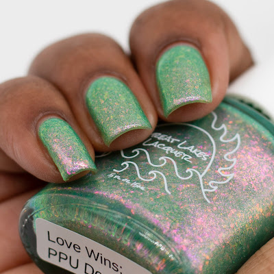 green nail polish with pink to green shifting flakes and shifting shimmer on dark skin