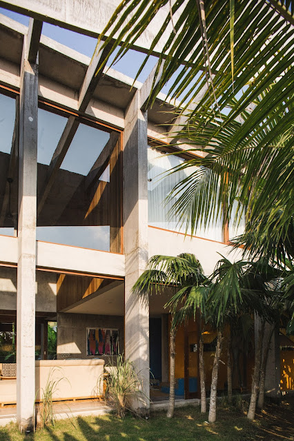 concrete geometric multi-level home with large windows and tropical landscaping