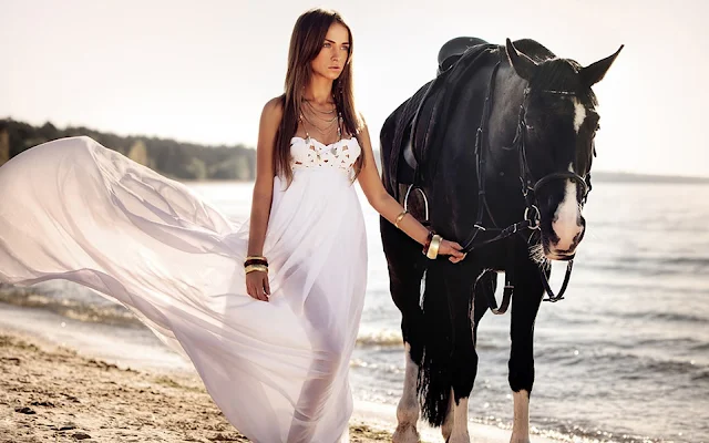 Een vrouw met haar paard op het strand