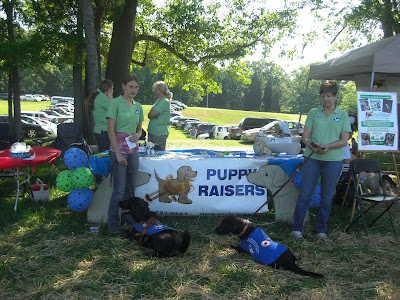 Picture of Rudy, Lexie (another guide dog puppy), I & Lexie's puppy raiser in front of our SEGDI booth
