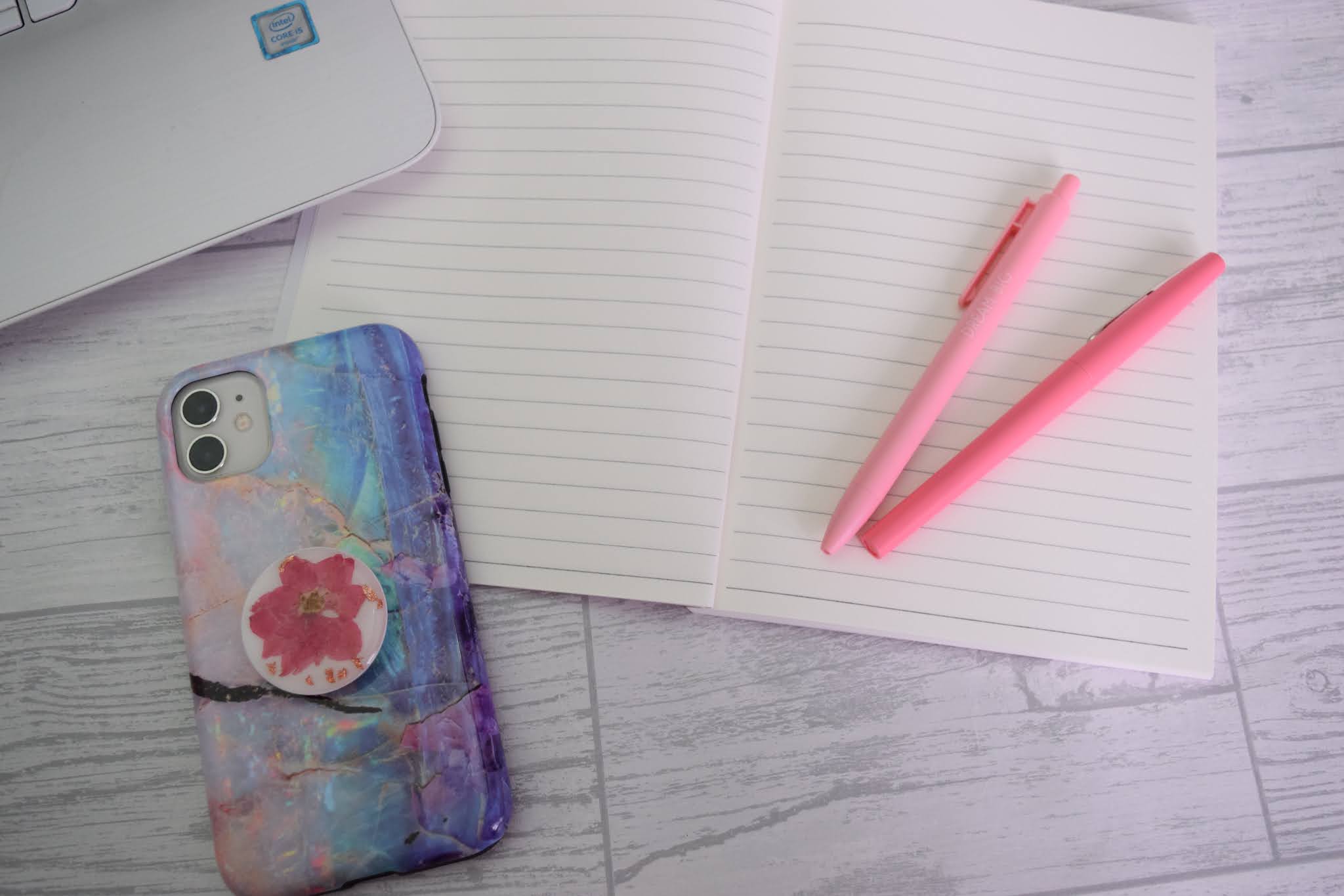Notebook opened up to lined pages with pink pens