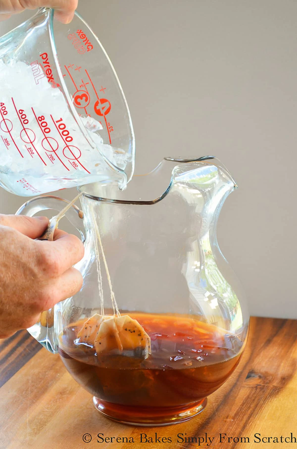 Iced Tea brewing in a large pitcher jar with ice being poured in.
