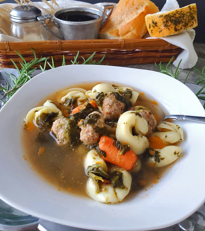this a tortellini soup in a chicken broth along rosemary sprigs, grated cheese and garlic bread