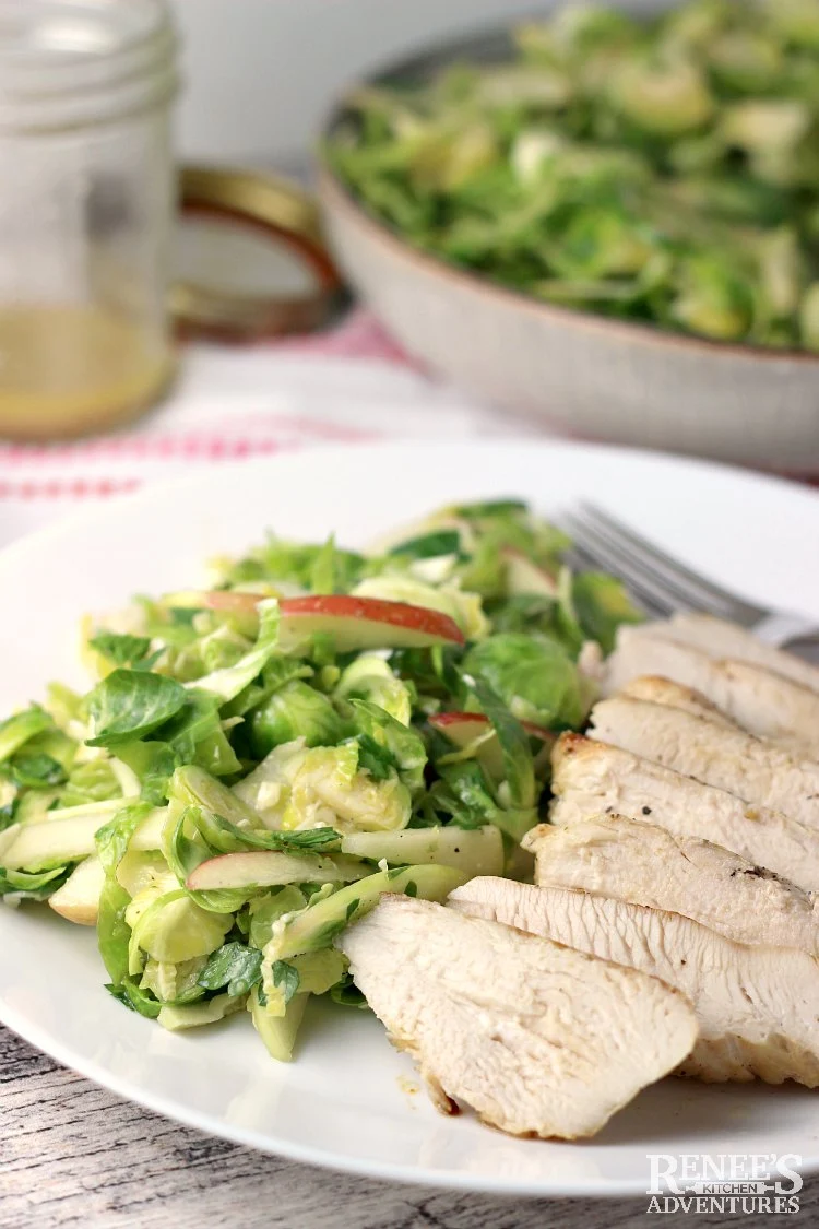 Shaved Brussels Sprouts Salad on plate with chicken as a serving suggestion
