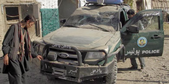 Petugas keamanan memeriksa sebuah mobil polisi yang hancur akibat serangan bom bunuh diri di Kandahar
