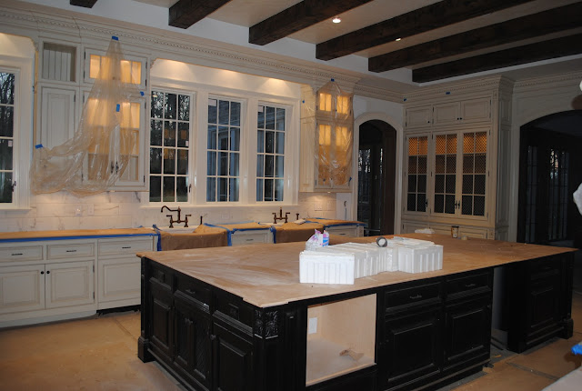 during construction of Enchanted Home Tina's French Country kitchen with white cabinets, wood beams, and black island