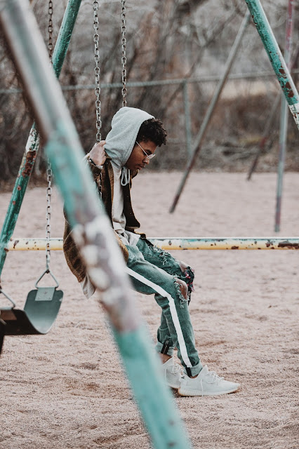 A boy sitting alone on swings on a playground