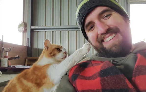 Barn cat taps man on face for more petting please