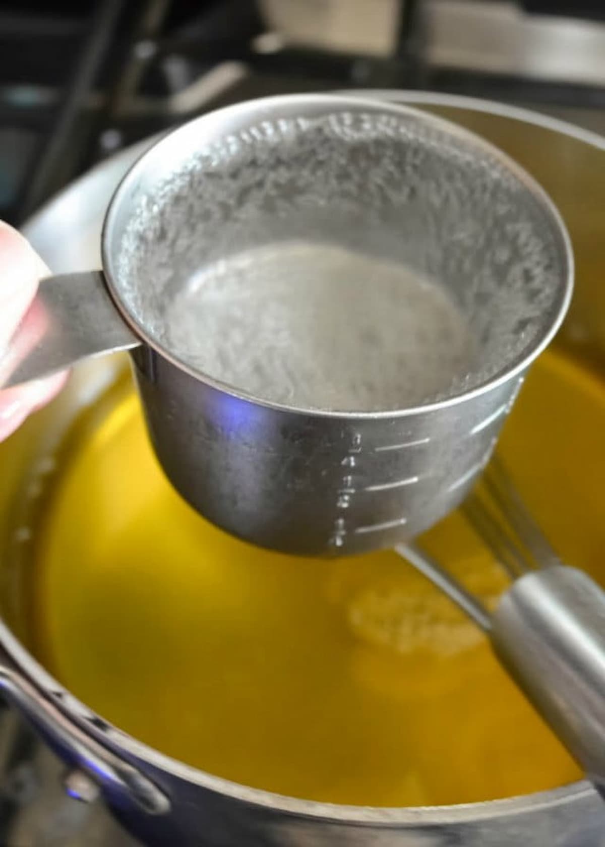 7 Up being stirred into Lemon Jello in a large sauce pan.