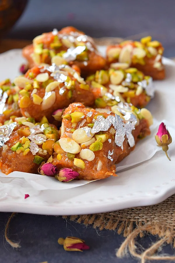 Close up of delicious carrot burfi placed on white plate ,garnished with lots of Pistachio