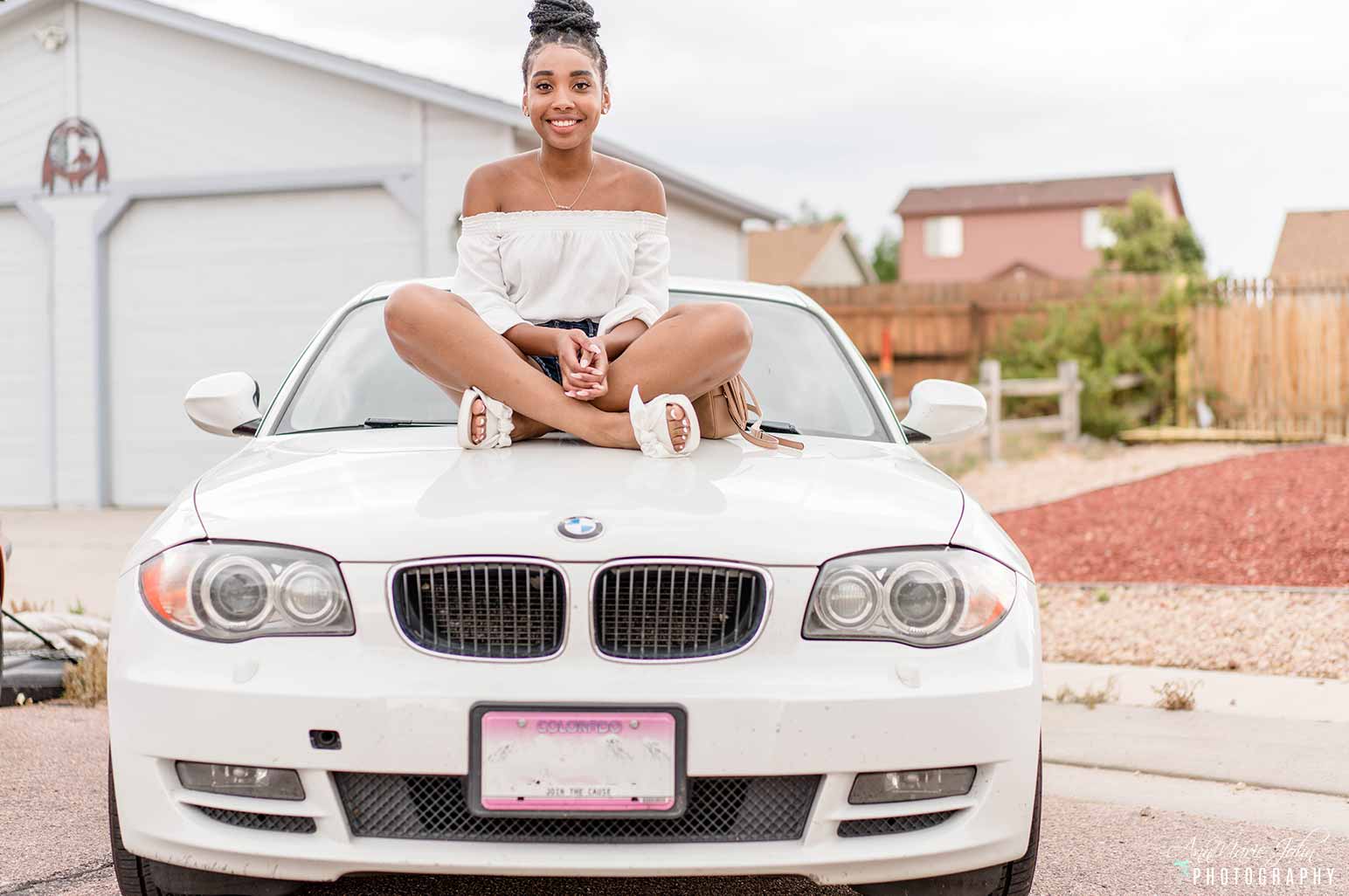 Teenager sitting on hood of car