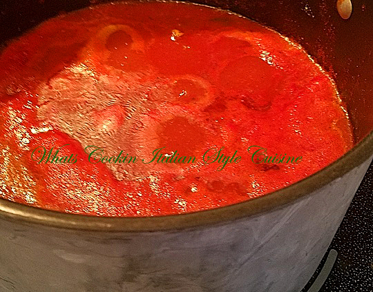 this is a pot of fresh red plum tomato sauce cooking on the glass stove top
