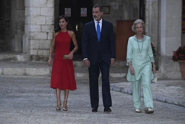 scoop neckline sleeveless fit and flare red dress. Dolce & Gabbana ready-to-wear collection, gold clutch. Queen Sofia