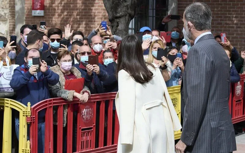 Queen Letizia wore a navy belted wool v-neck midi dress from Massimo Dutti, and white cashmere coat from Carolina Herrera