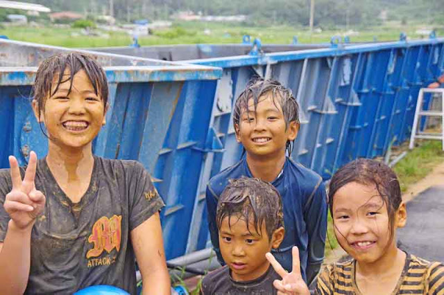 children,mud,smiles, peace signs