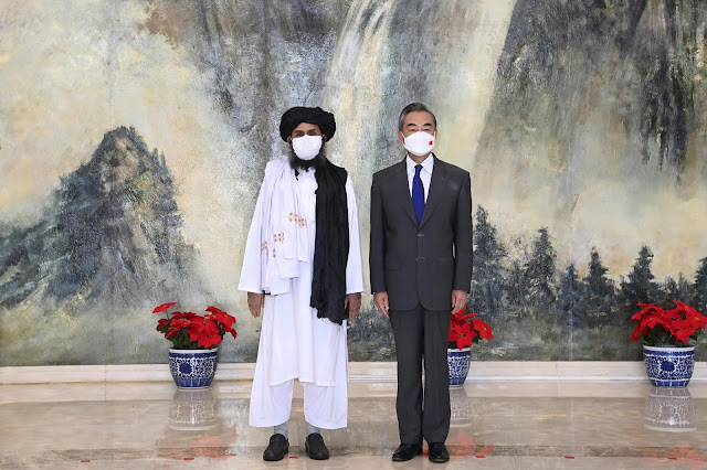 Taliban co-founder Mullah Abdul Ghani Baradar, left, and Chinese Foreign Minister Wang Yi pose for a photo during their meeting in Tianjin, China