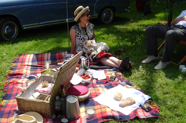 Schönes Picknick Arrangement mit karierter Decke und schlafenden Hund auf den Beinen der Besitzerin karierte Picknick Decke mit Korb und Frau mit Hund auf den Beinen auf Schloss Merode