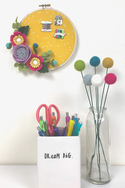 enamel pins stored in embroidery hoop wreath embellished with felt flowers