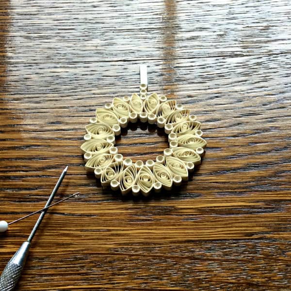 applying dots of glue to joins on reverse side of quilled pendant