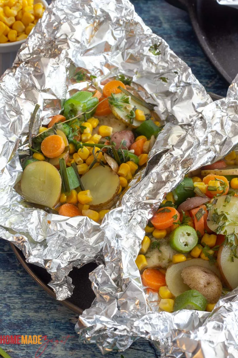 Foil packet showing baked tilapia with corn, okra, potatoes