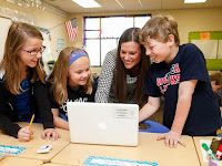 3 students and 1 teacher looking at a laptop