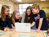 3 students and teacher looking at laptop