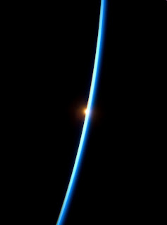 Bright blue curve in dark space, sun visible below the horizon