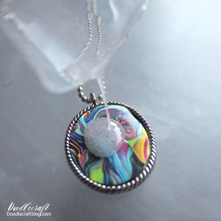 Supplies needed to make an acrylic paint poured dried skin pendant necklace with jewelry resin and silver plated bezel diy.