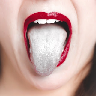 Image of a red lipsticked mouth, top teeth slightly visible, open with a tongue protruding far out. The tongue is entirely gray, though the rest of the image is in full color.