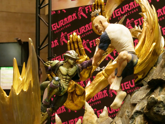 Statue of Meruem a green Chimera ant monster fighting an old man Netero who summoned a giant golden buddha