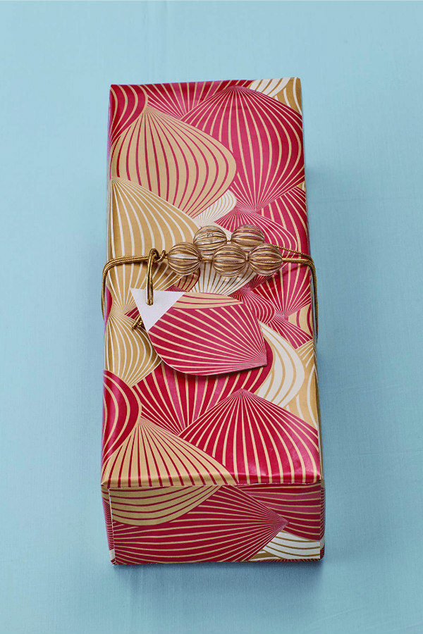 red and gold gift wrapped present with leaf-shaped gift tag and beaded gold cording