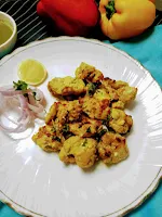 Serving chicken reshmi kabab in a plate with onion sliced and lemon wedges.