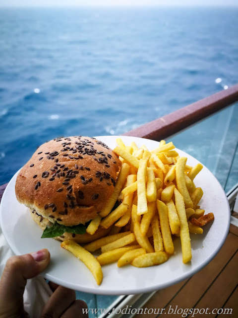 Burger mit Pommes von der Poolbar Cliff24, im Hintergrund das Meer