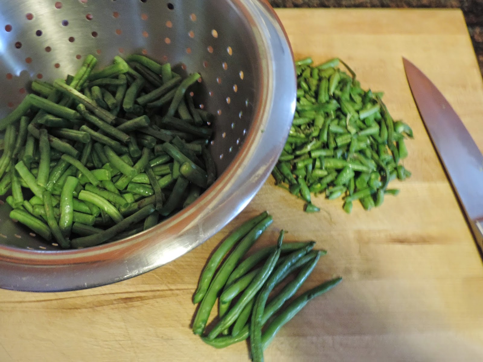 The green beans being trimmed and put in a strainer.  