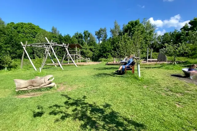 A view from the entrance of Hanningfield reservoir playground showing 2 large climbing frames with slides, swings and more