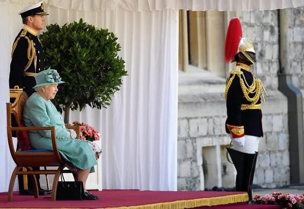 Queen is wearing a Stewart Parvin outfit, plus a floral silk dress with pleated hem detail, in shades of jade grey and dusty pink