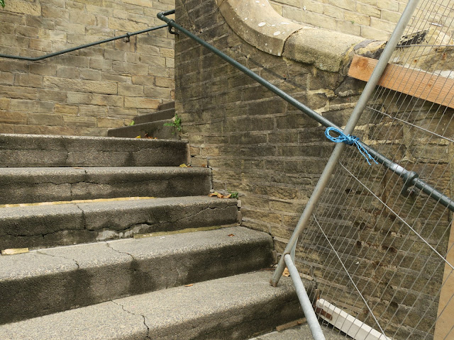 Stone steps with hand rail between stone walls.