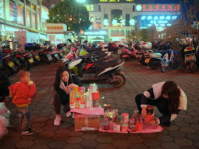 young woman setting up a display of Christmas apples in Zhongshan