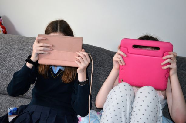 two girls with ipads in front of faces