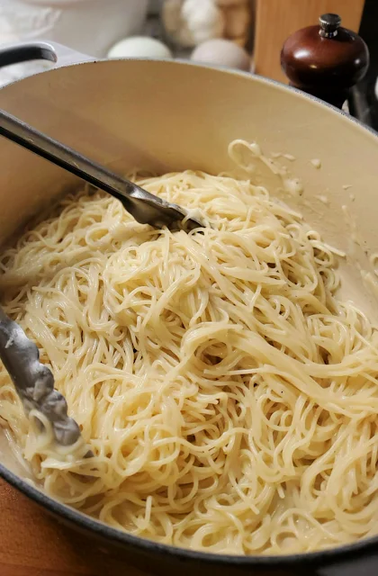 tongs grabbing pasta in pot