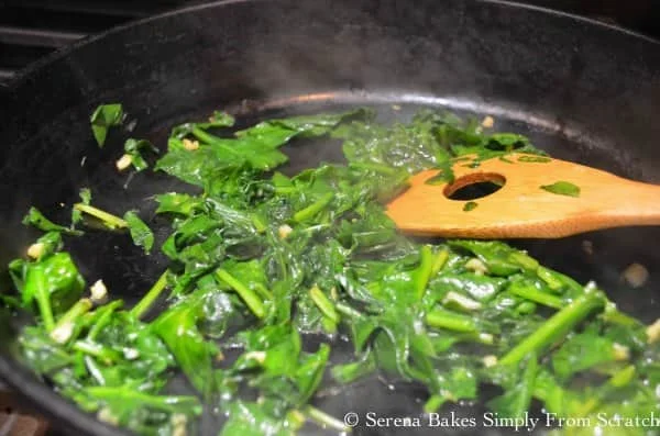 Garlic and Spinach being cooked in a pan for Hot Spinach Artichoke Dip.