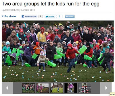 Children running into a field of green grass to grab eggs while a crowd looks on