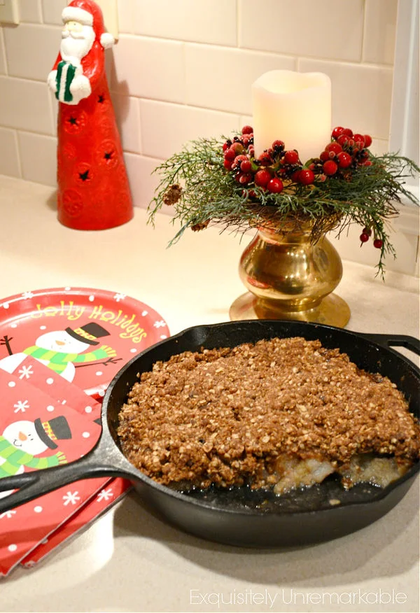 Apple Crisp in a cast iron pan on a table with Santa