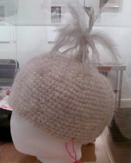 Crocheted beanie-style hat made of raw handspun wool embellished with emu feathers.