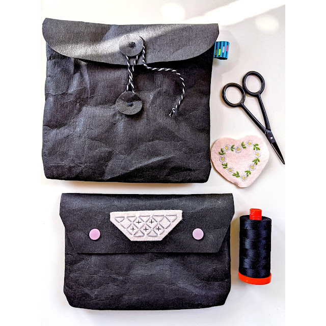 Two pouches made from paper fabric, an embroidery patch, scissors and a spool of thread