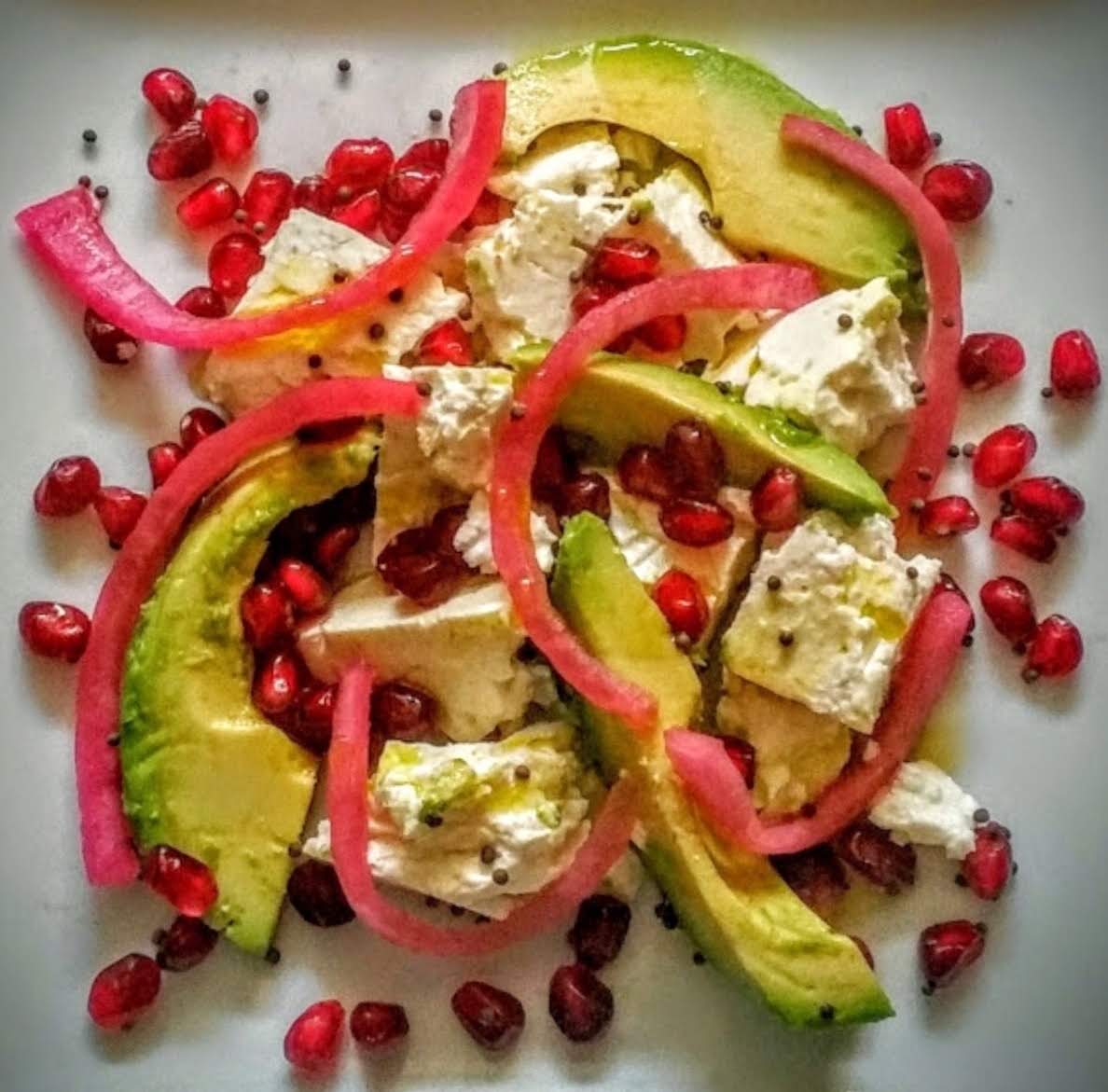 feta and avocado salad with red onions, pomegranate, and nigella seeds