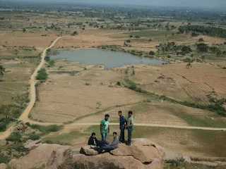Hikers take a small break ontop of a view post overlooking the open lands at the Bhasmangi Fort hill